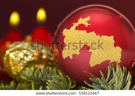 A glossy red bauble with the golden shape of Tajikistan.(series)