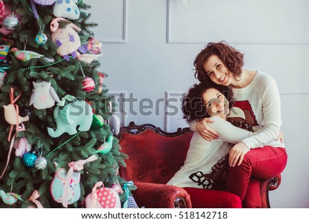 beautiful and happy twins with curly hair sits near christmas tree