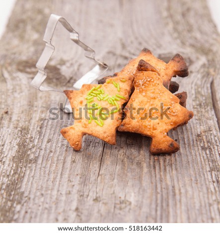 Christmas tree shaped cookies and cookie cutter on wooden background