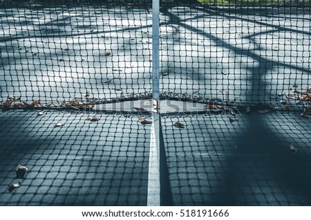 Abstract tennis court center with fallen leaves clay court. Isolated tennis court net. Light and shadow on center court. Minimal design and art. Abstract outdoor sports. Fall season on tennis court.