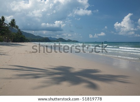 Shadow of Palm on the sandy beach with islands in the background