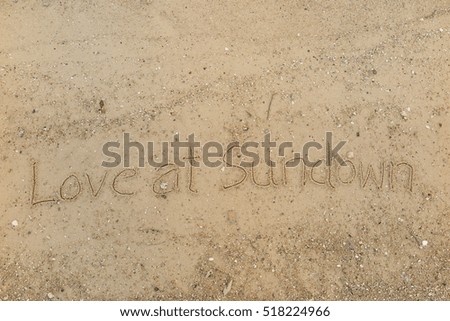 written words "Love at Sundown" on sand of beach