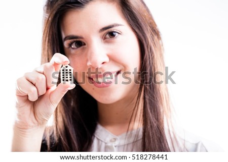 portrait of a smiling woman holding a little house in her hand