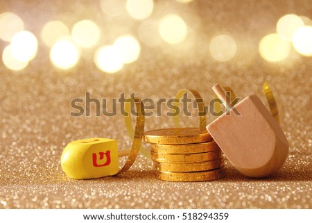 Image of jewish holiday Hanukkah with wooden dreidel (spinning top) and chocolate coins on the glitter background