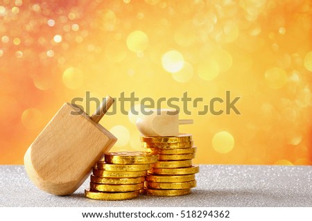 Image of jewish holiday Hanukkah with wooden dreidel (spinning top) and chocolate coins on the glitter background

