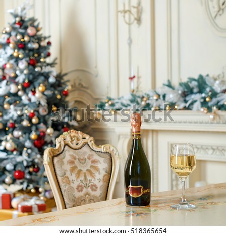 Bottle of white wine and glass on the table in beautiful holiday decorated room for Christmas celebrations. New Year decorations.