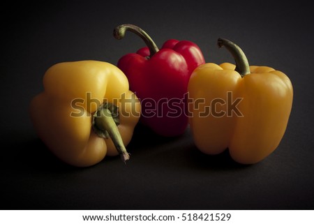 Red and yellow peppers isolated on dark background. Still-life picture taken in studio with light-box.