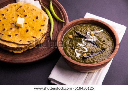 Makki Ki Roti & Sarson Ka Sag is basically Corn floor flat bread & curry using mustard greens respectively. Popular Punjabi food. Served in wooden bowl and plate over moody background. selective focus