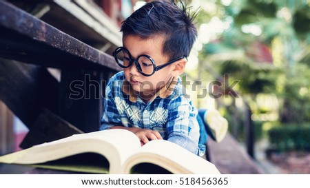 Little boy reading a book on the wooden floor