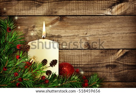 Christmas corner decoration with pine twigs, candle and balls on brown wood background