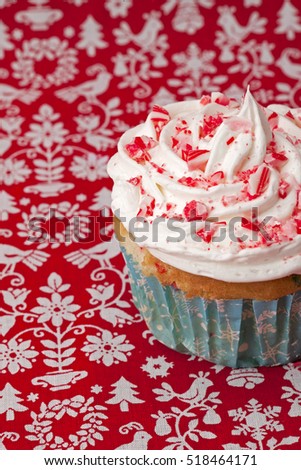 Decorated cupcake with pink sprinkles and candy cane and red background