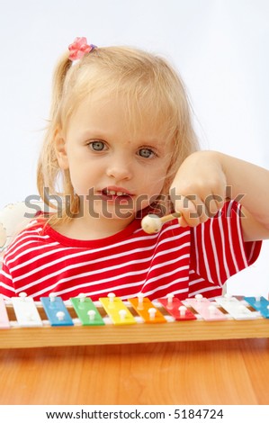 Little girl wearing striped red t-shirt playing the rainbow xylophone
