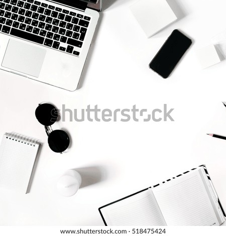Square crop. Stylish minimalistic workplace with laptop keyboard, smartphone, notebook, sunglasses in flat lay style. White background. Top view.