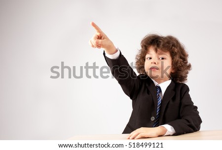 Business boy shows a finger to the right, looking at the camera. Gray background. Close-up.