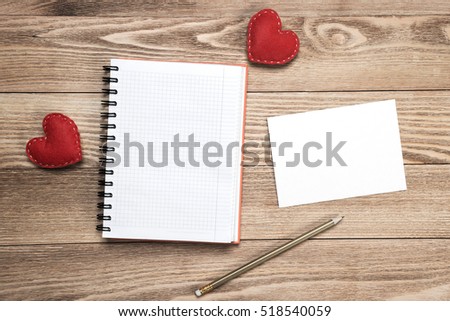 Hearts and notepad sheet of blank paper on wooden table