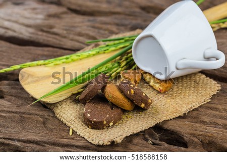 Chocolate cookies on white linen napkin on wooden table and heart white cup