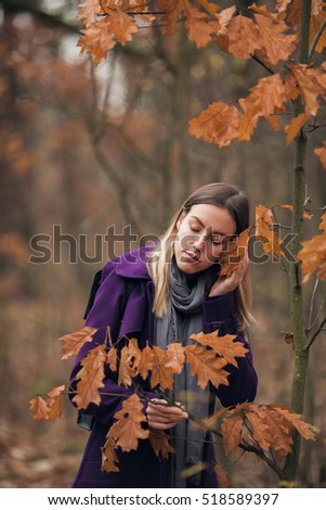 Young girl in violet coat getting some inspiration in autumn forest. Calm walk. Casual fashion. Piece of fairytale