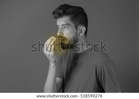 Bad breath. Halitosis concept. Young man checking his breath with his hand. Royalty-Free Stock Photo #518590276