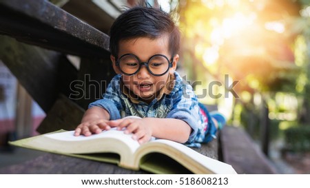 Little boy reading a book on the wooden floor
