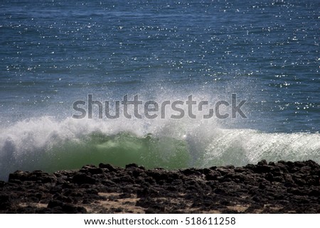 Spectacular backwash from the  Indian Ocean waves breaking on basalt rocks at  Ocean beach Bunbury Western Australia on a sunny morning in early spring  sends salty spray high into the air.