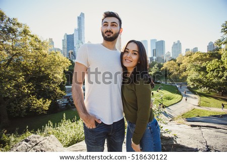 Beautiful multiracial couple taking picture in Central Park, New York. Young and funny multicultural students take photo for travel blog.
