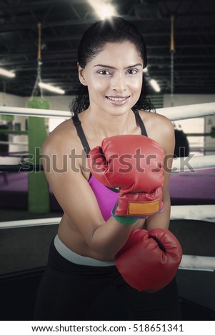 Picture of female boxer with her red gloves guarding herself and getting ready to attack in the ring