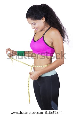 Picture of Indian woman wearing sportswear and measuring waist with tape in the studio