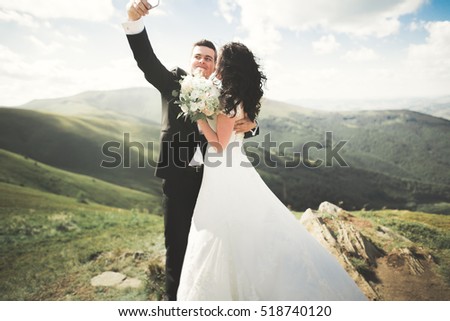Beautiful young wedding couple making selfie on the background of mountains