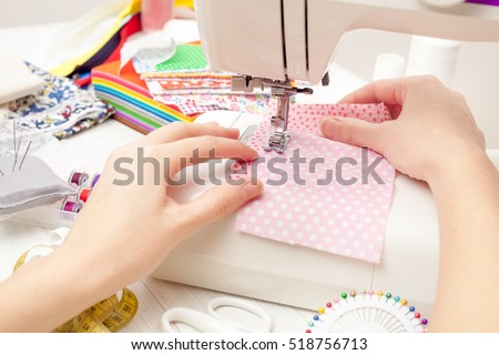 sewing, sewing on the sewing machine, sewing supplies, colored sewing threads, colored pieces of cloth, needles, centimeter, tailors scissors on white wooden background Royalty-Free Stock Photo #518756713