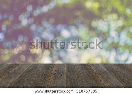 Abstract bokeh sunlight and tree background of nature in green color with wood terrace