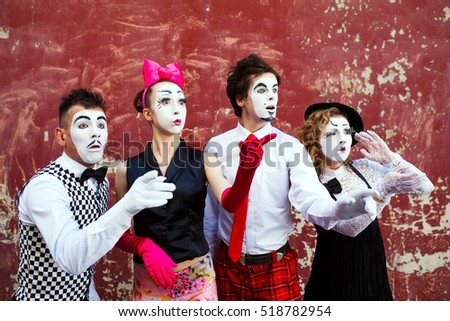 Four mimes looking aside on the background of a red wall. Royalty-Free Stock Photo #518782954