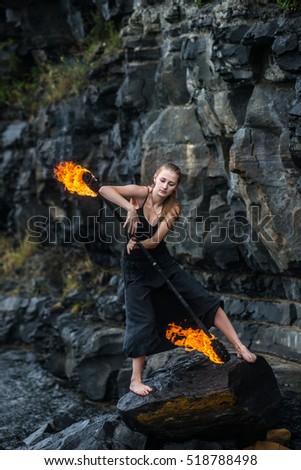 Girl in a black suit with flaming torches. fire