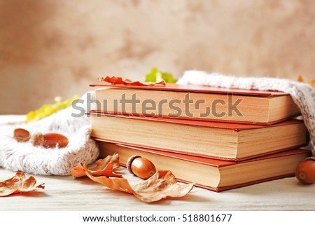 Books with warm scarf and autumn leaves on the table