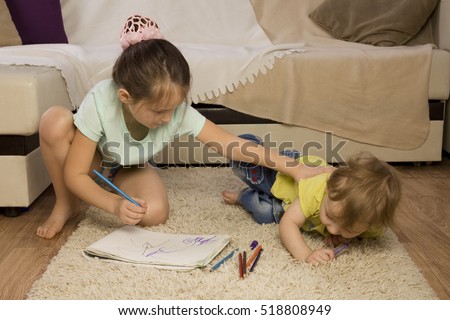 The conflict between a boy and a girl. Older sister younger brother offends. Sister takes his brother's pen. Children quarrel over the drawing. Children with paint. siblings Psychology.