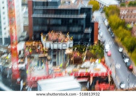 Multiple exposure effect image. Building site view with cranes and workers. View includes side street with cars.