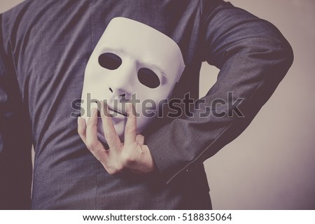 Business man carrying white mask to his body indicating Business fraud and faking business partnership Royalty-Free Stock Photo #518835064