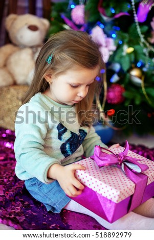 beautiful baby opens a gift. The concept of Christmas and a happy new year.