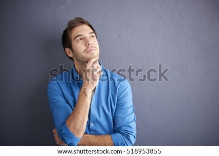 Cropped shot of thoughtful young man standing by the wall. Royalty-Free Stock Photo #518953855
