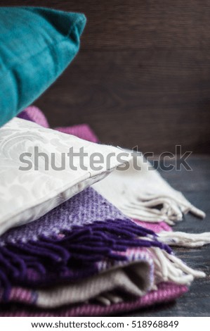 Colorful pillows  and plaid stacked on dark wooden chair