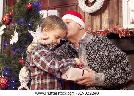 adorable little boy gives a christmas gift to his grandfather