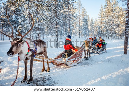 Family with kids at reindeer safari in winter forest in Lapland Finland