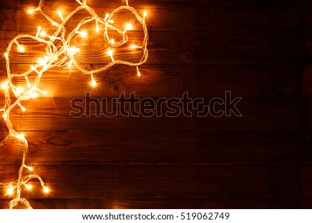 Dark brown wooden background with shining garland on the left