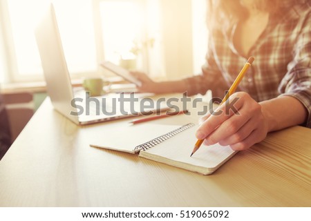 hand with pencil and notebook at workplace