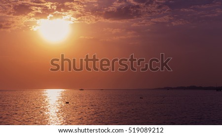 Warm red and yellow cloudy sky and sea. Sunset or sunrise picture with horizon. Background banner. Dim dark light, toned image