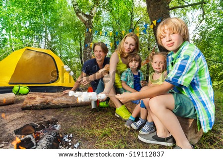 Happy family roasting marshmallows in the woods