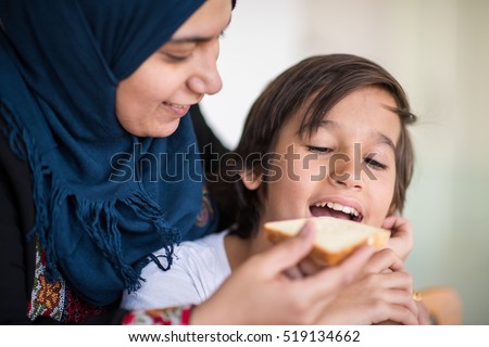 Muslim traditional woman with son at kitchen