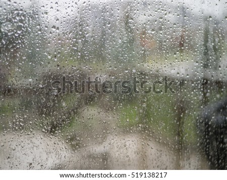Raindrops on a steamy patio glass door looking out at a suburban street in Fall.  Shallow Depth of Field.