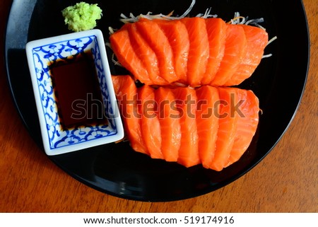 Salmon raw sashimi with shoyu and wasabi on wooden table