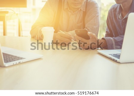 man holding pen reading text message on mobile phone in network,sitting with laptop computer in co-working cafe.Group of friends are using gadgets during recreation time in coffee shop.vintage color

