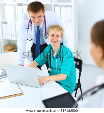 Beautiful young smiling female doctor sitting at the desk